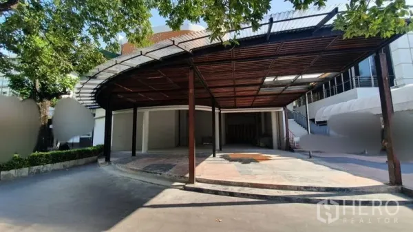 Retail Space for rent in Khlong Toei, Bangkok - Wide approach to the unit showing shaded canopy, open forecourt and neighboring commercial buildings.