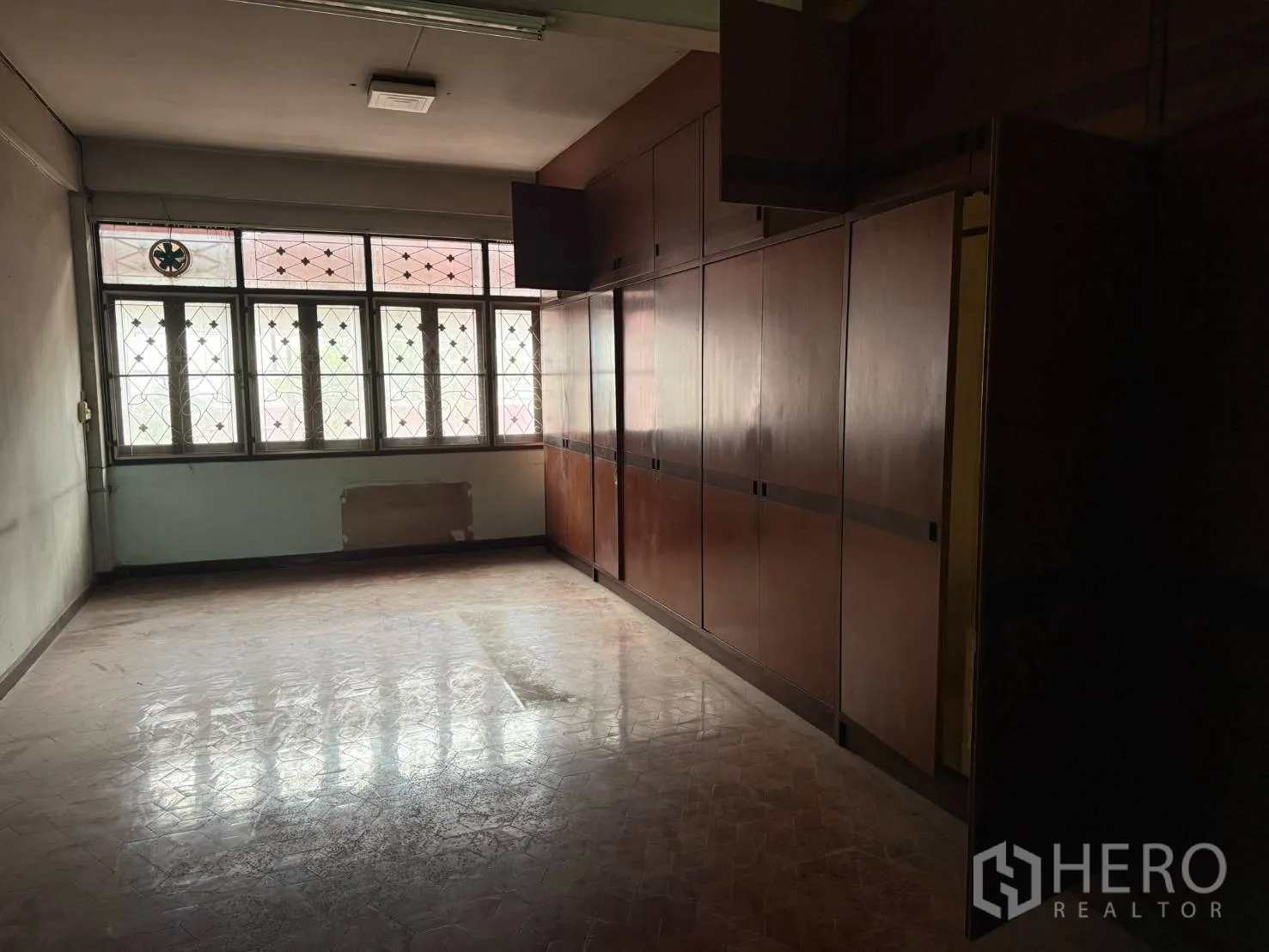 Shophouse for rent in Khlong Toei, Bangkok - Upper room featuring long built-in wooden cabinets and front windows.