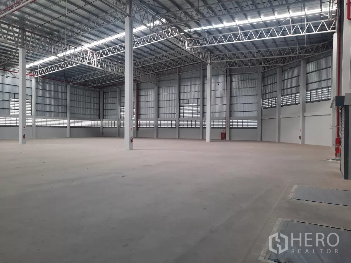 โรงงาน ให้เช่าในBang Lamung, Chon Buri - ผนังโกดังติดตั้งประตูม้วนหลายบานและป้ายทางออกฉุกเฉิน