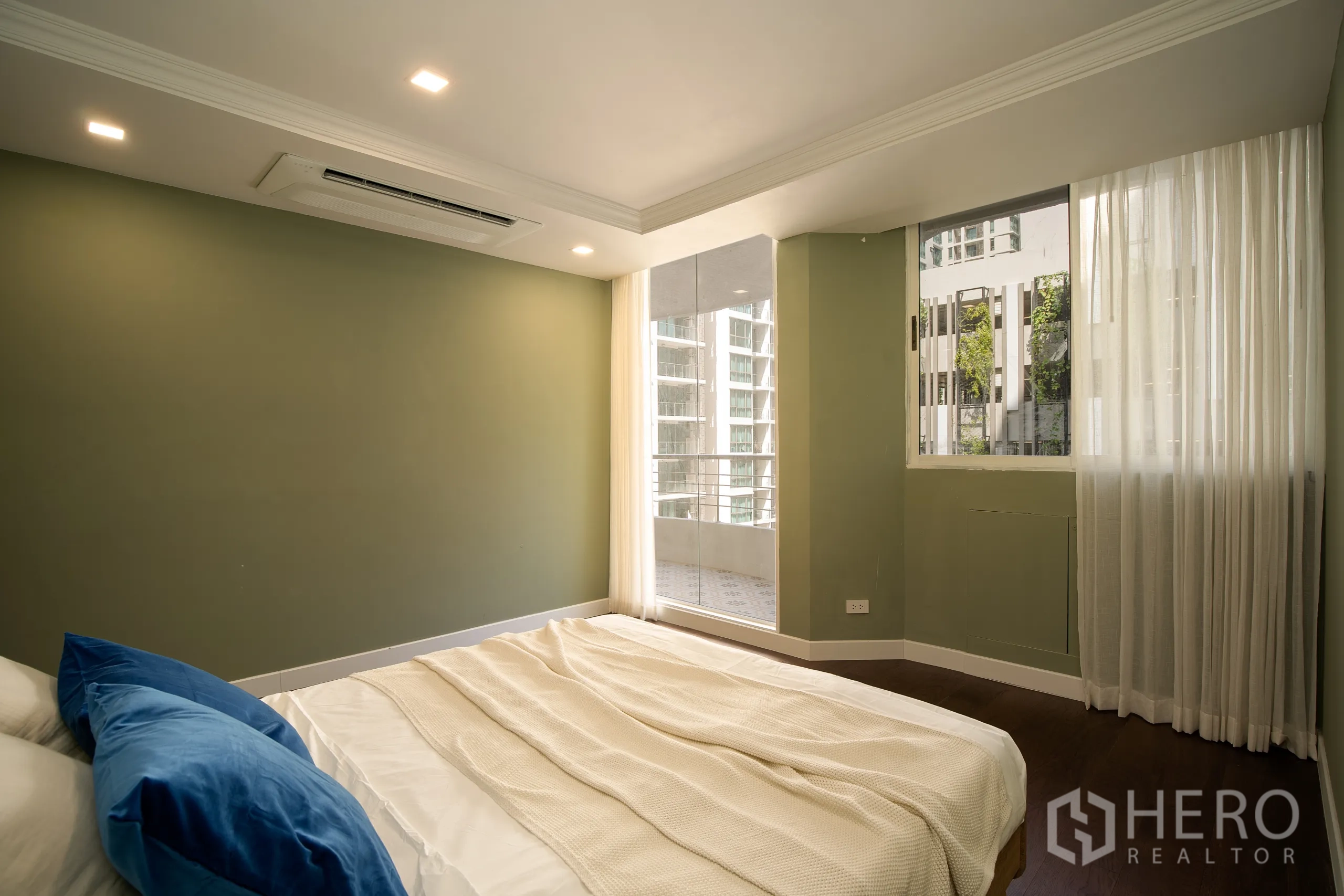 Condominium for sale in Watthana, Bangkok - Guest bedroom with green walls and balcony access in Phrom Phong condominium.