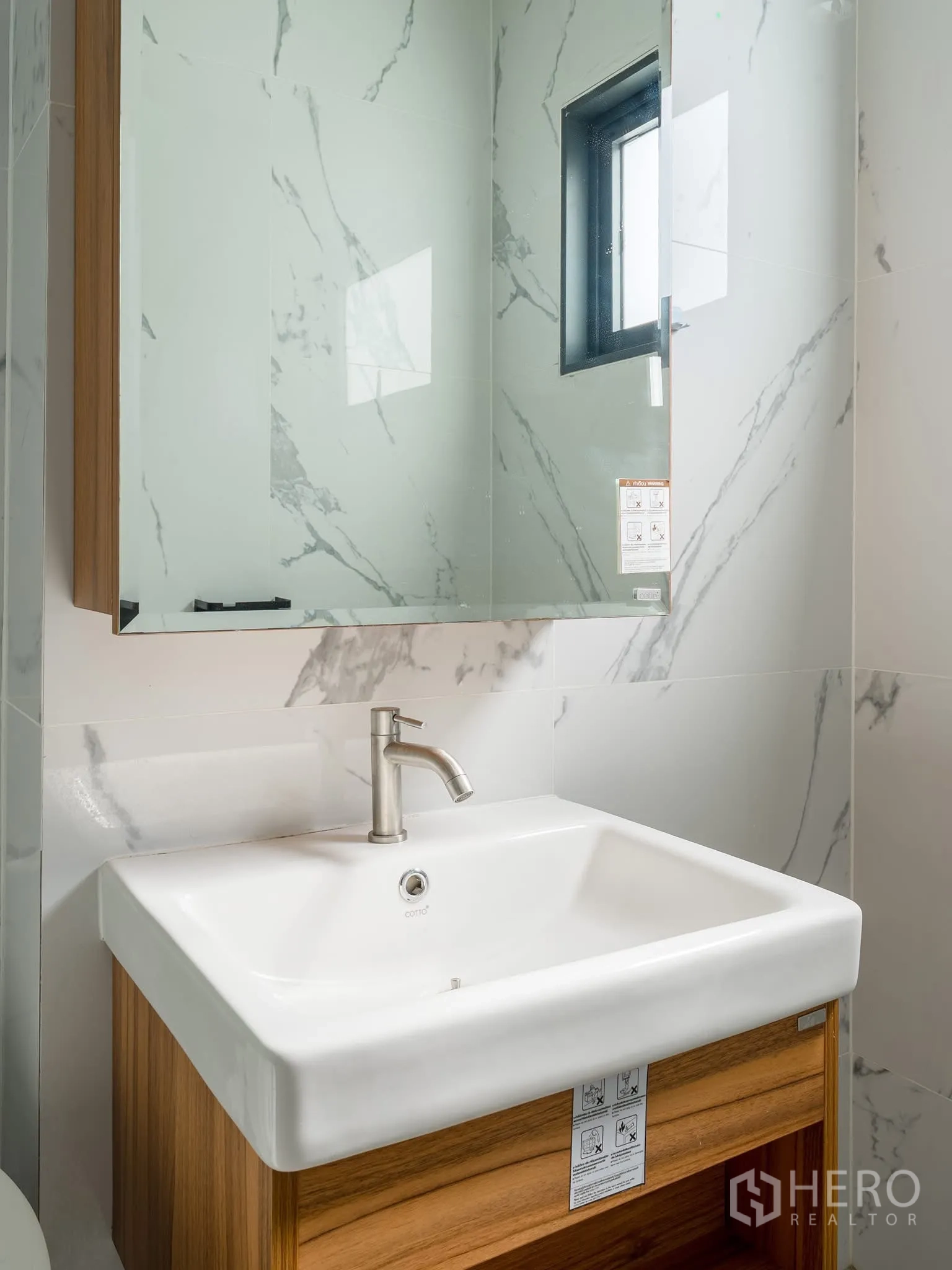 Home Office for rent in Khlong Toei, Bangkok - Close-up of sink and mirror cabinet with wood surround in a bright bathroom.