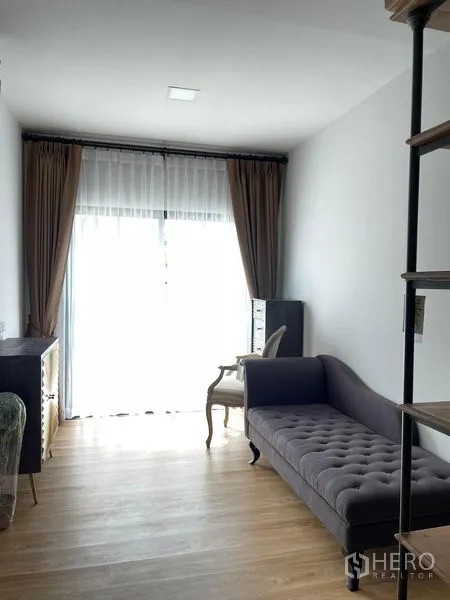Townhouse for rent in Samut Prakan - Lounge area with tufted daybed, floor-to-ceiling window and wood flooring.