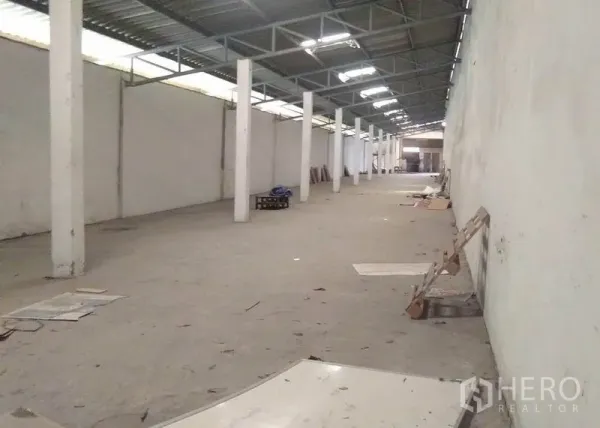 Factory for rent in Bang Phli, Samut Prakan - Long warehouse aisle with columns and metal roof featuring skylight panels for ventilation.