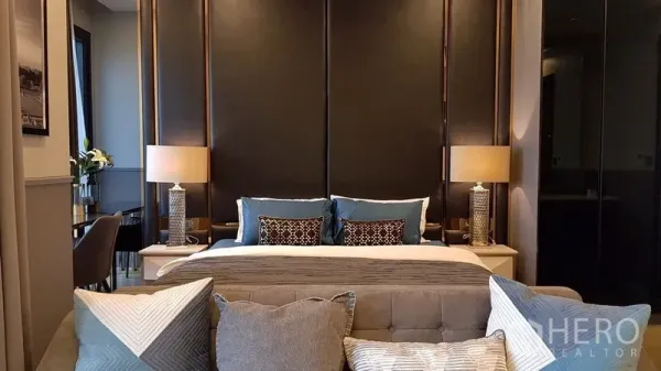 Condominium for rent in Watthana, Bangkok - Cozy bedroom with upholstered headboard, twin bedside lamps and a grey sofa at the foot of the bed.