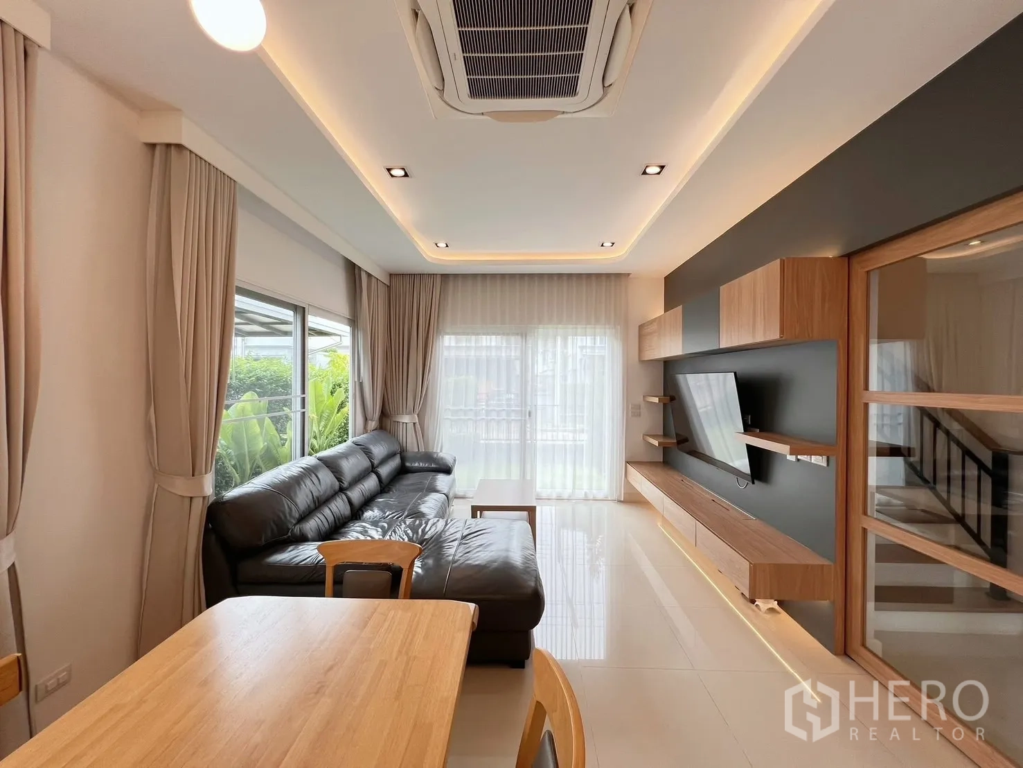 Detached House for rent or sale in Khlong Luang, Pathum Thani - Bright living area with black leather sofa, large windows and sliding door to garden.