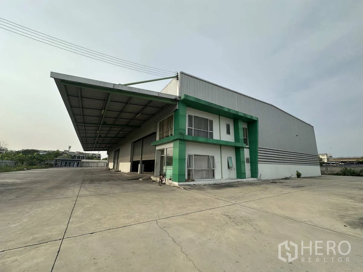 โรงงาน ให้เช่าในMueang Samut Prakan, Samut Prakan - มุมมองด้านข้างของโรงงาน แสดงถนนภายในกว้าง กันสาดลึก และประตูโหลดหลายจุด