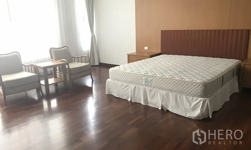 房间 出租在Watthana, Bangkok - 宽敞卧室，床垫与休闲椅角落，木地板，采光良好。