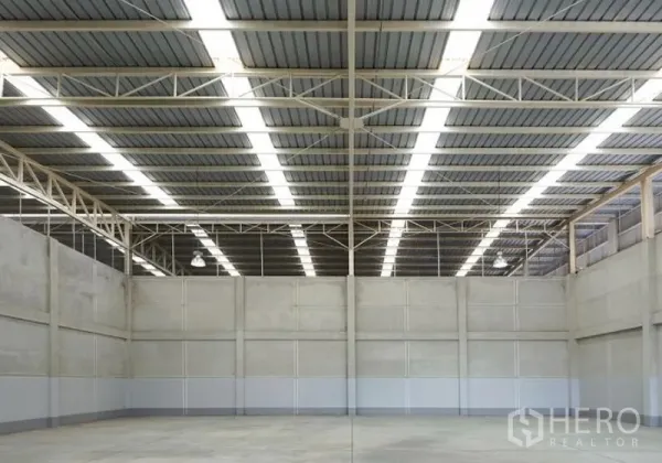 Factory for rent in Pluak Daeng, Rayong - Clear-span factory floor with tall concrete walls and continuous skylight-style roof panels.