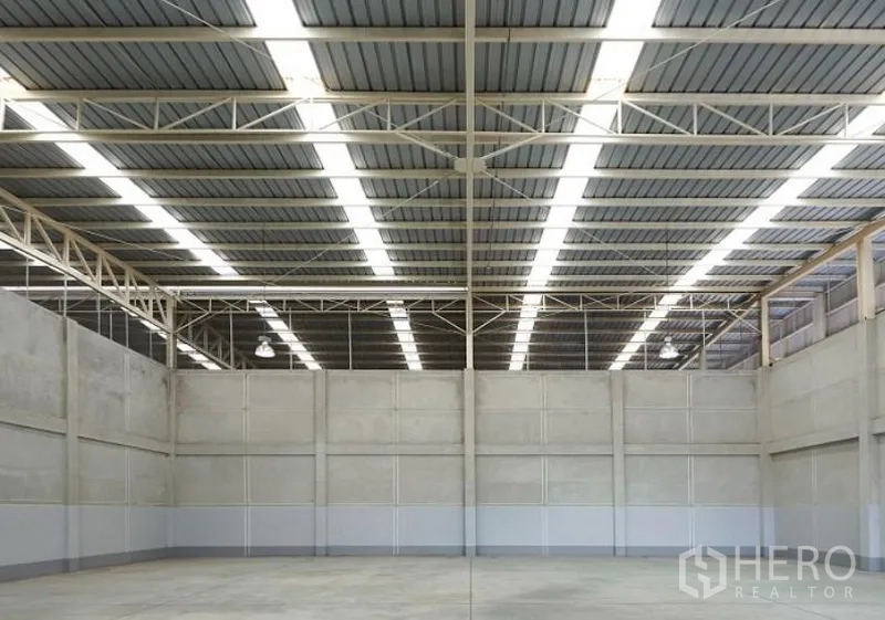 Factory for rent in Pluak Daeng, Rayong - Clear-span factory floor with tall concrete walls and continuous skylight-style roof panels.