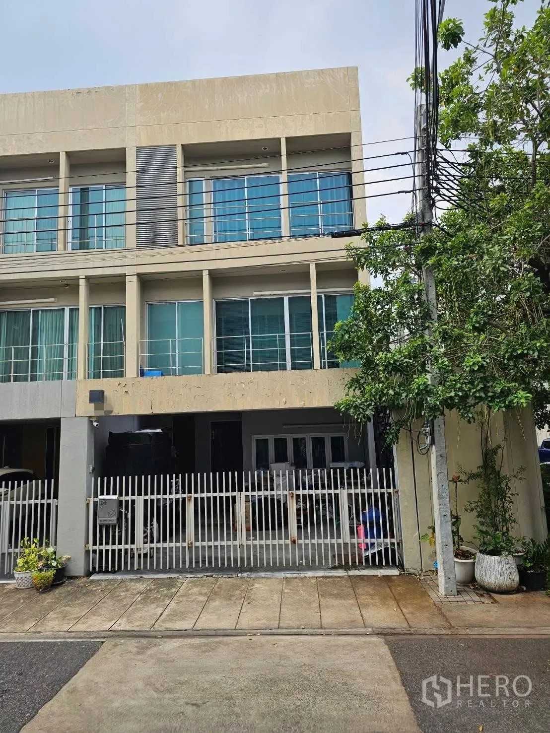 ทาวน์เฮาส์ for sale in Suan Luang, Bangkok - ด้านหน้าทาวน์เฮ้าส์สูงสามชั้น กระจกกว้าง ระเบียง และรั้วหน้าบ้าน