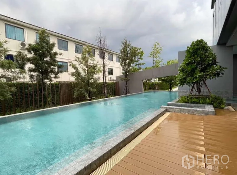 Townhouse for rent in Bang Phli, Samut Prakan - Long outdoor swimming pool with wooden deck, trees and landscaped garden.