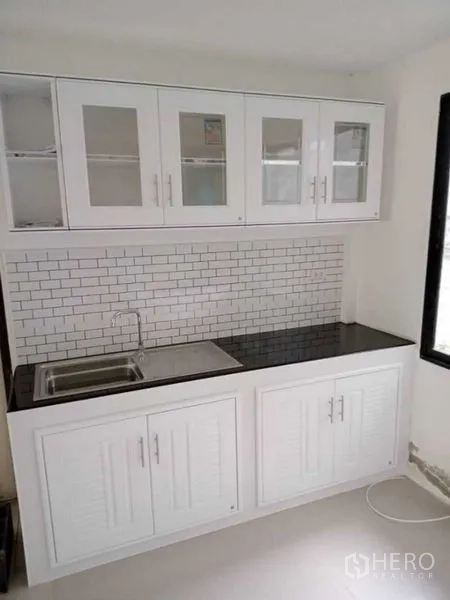บ้าน ให้เช่าในPrawet, Bangkok - มุมอ่างล้างจาน ตู้แขวนกระจก เคาน์เตอร์ท็อปสีดำ และผนังกระเบื้องลายอิฐ