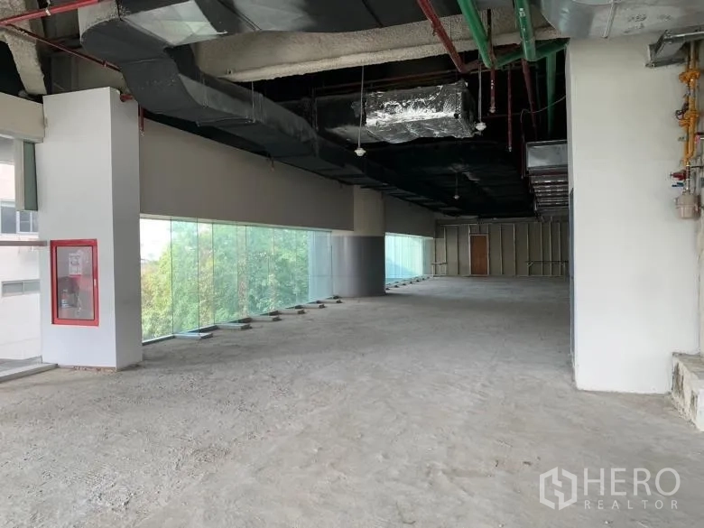 零售空间 出租 - 宽阔毛坯零售区，通透玻璃墙与高挑裸顶。