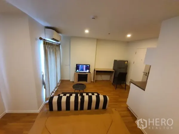 公寓 出售在Chatuchak, Bangkok - 乍都节公寓客厅，条纹沙发、电视、书桌与冰箱，木地板温馨明亮。