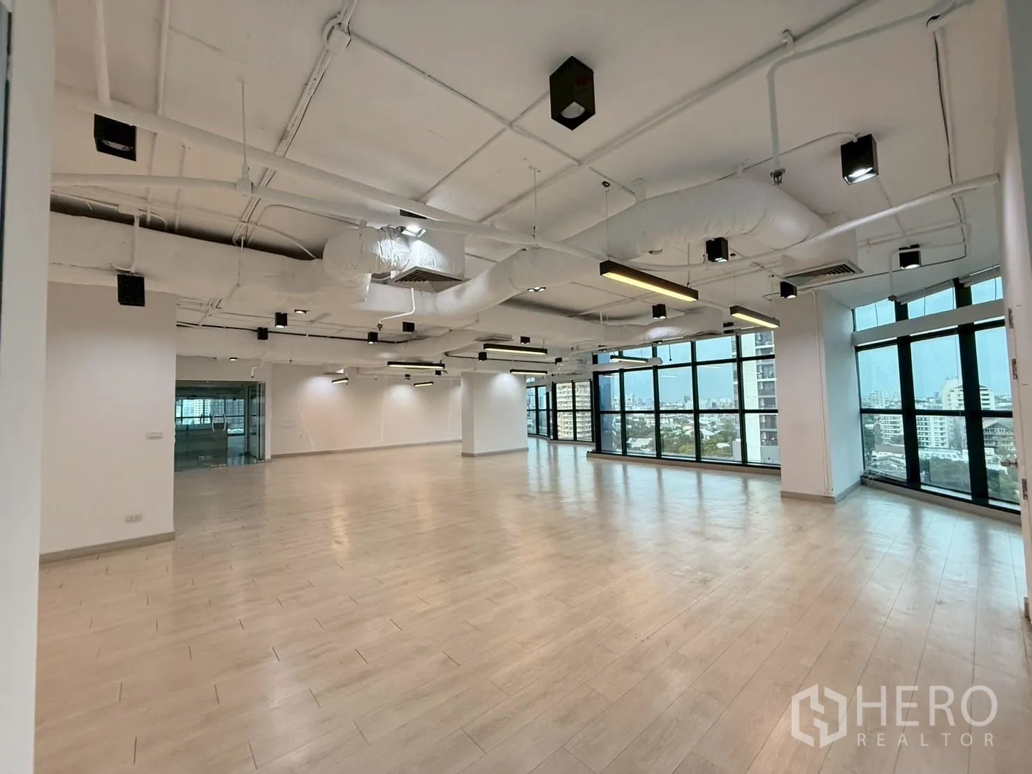 办公室 for rent in Watthana, Bangkok - 宽敞开放式办公室，外露风管、吊灯与全景窗户。