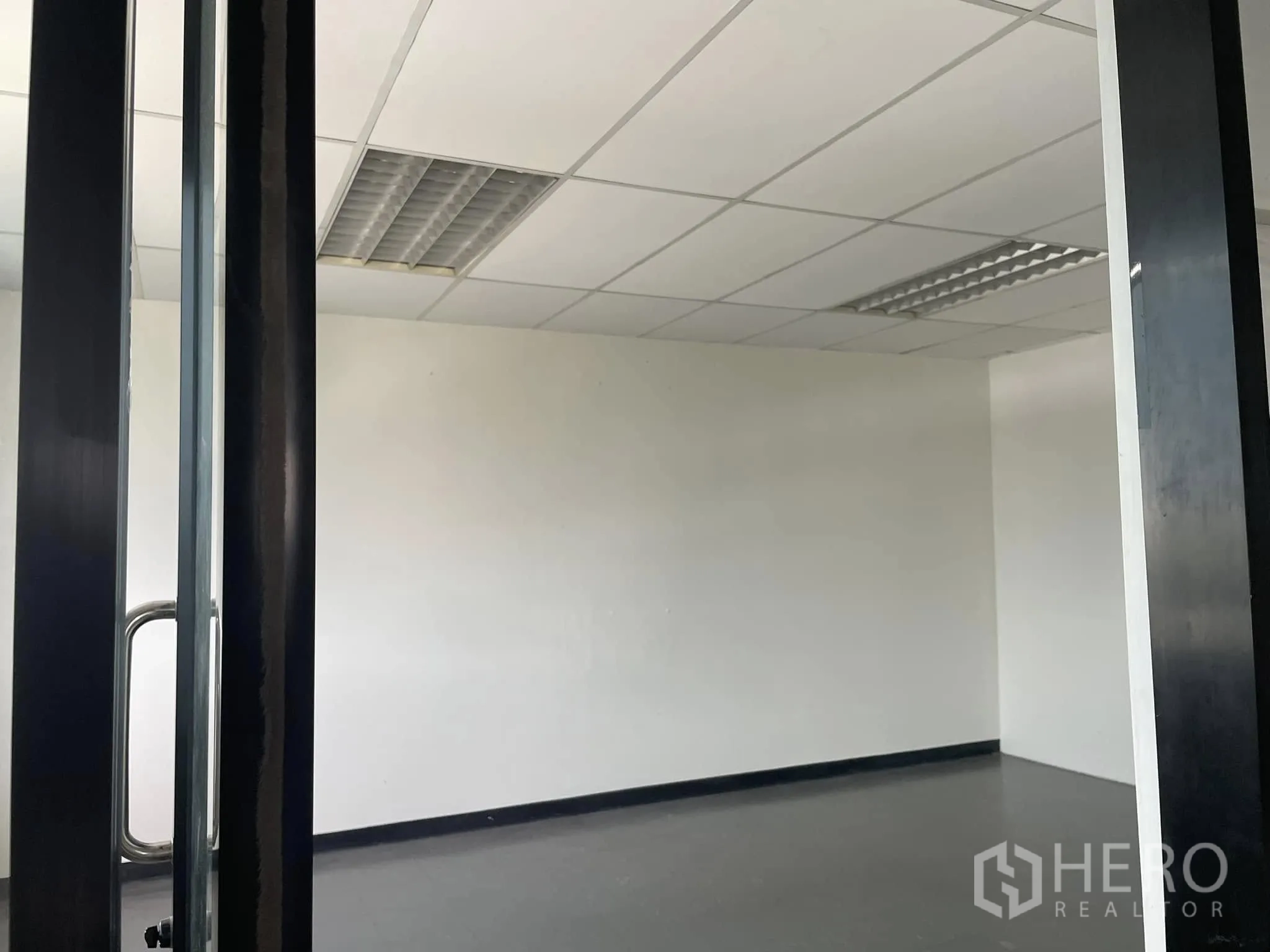 办公室 for rent in Lat Phrao, Bangkok - 小型办公室，带玻璃门、白色墙面与格栅吊顶灯。