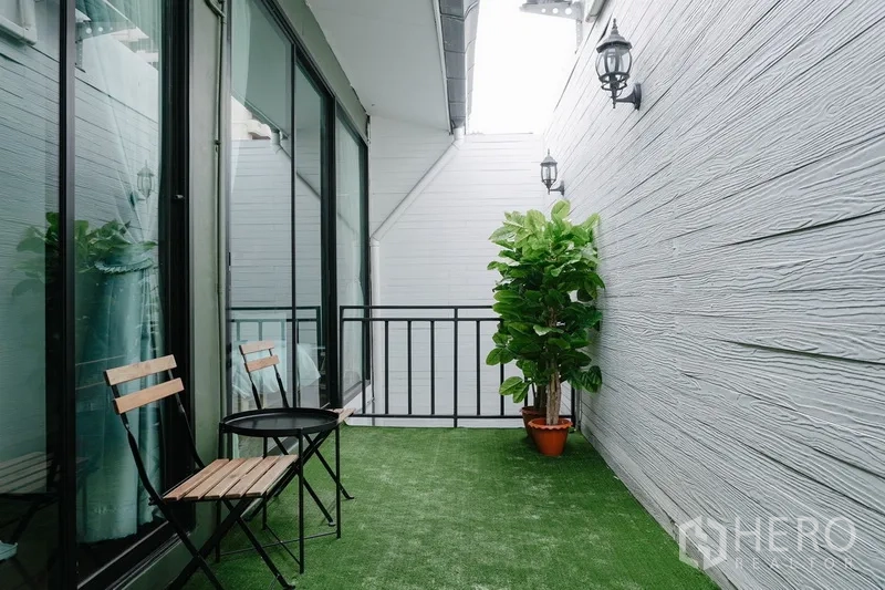 联排别墅 出租在Watthana, Bangkok - 私密阳台，人工草坪，小圆桌椅与玻璃推拉门。