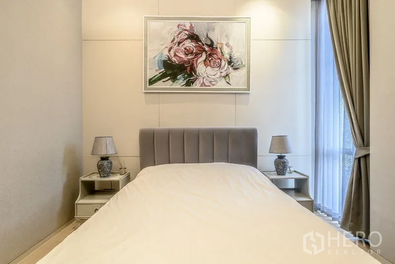 คอนโด ขายในWatthana, Bangkok - ห้องนอนแขก หัวเตียงบุผ้า โต๊ะข้างเตียง และภาพวาดดอกไม้ริมหน้าต่าง