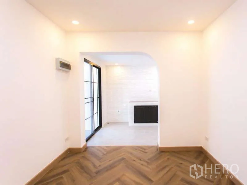 Detached House for sale in Wang Thonglang, Bangkok - Cozy room with arched doorway leading to the tiled kitchen and a black-framed sliding door.