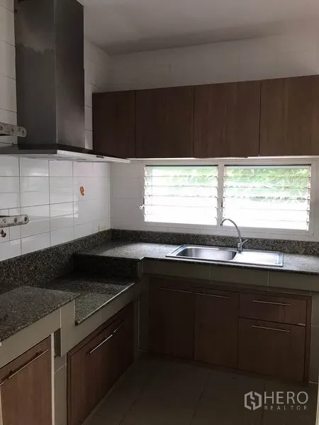 独立式住宅 出租在Khlong Sam Wa, Bangkok - 独立厨房，花岗岩台面、窗下水槽与木质橱柜。