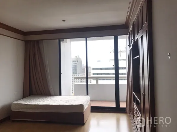 Condominium for rent in Pathum Wan, Bangkok - Spacious bedroom with built-in wardrobe and sliding doors to a private balcony.