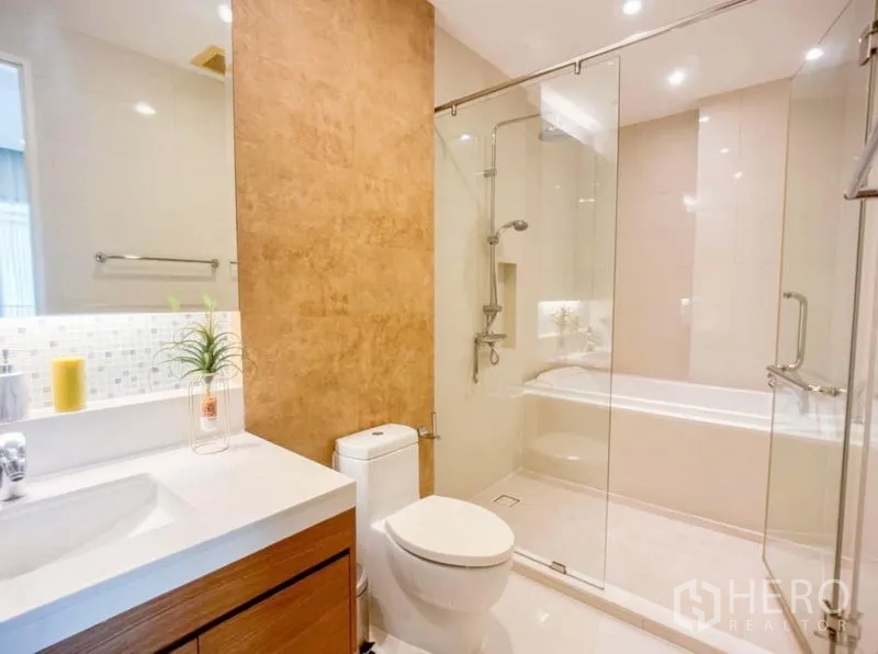 Condominium for rent in Khlong Toei, Bangkok - Ensuite bathroom with glass-enclosed shower, bathtub, vanity and soft lighting.