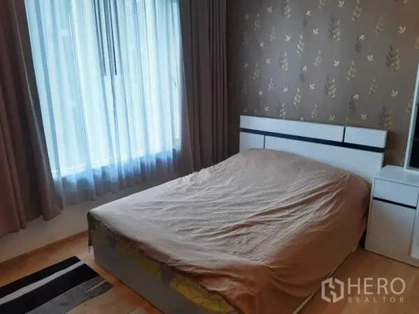 Condominium for rent in Khlong Toei, Bangkok - Cozy bedroom with a double bed, feature wallpaper, large window, and blackout drapes.