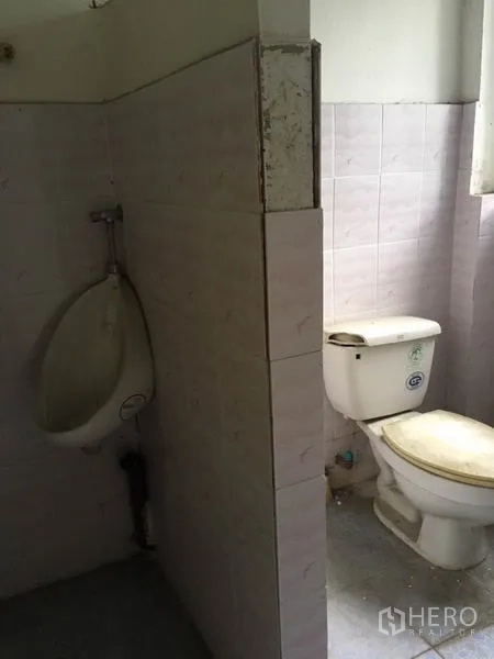Shophouse for rent in Khlong Toei, Bangkok - Restroom with urinal and toilet against pale pink ceramic tiles.
