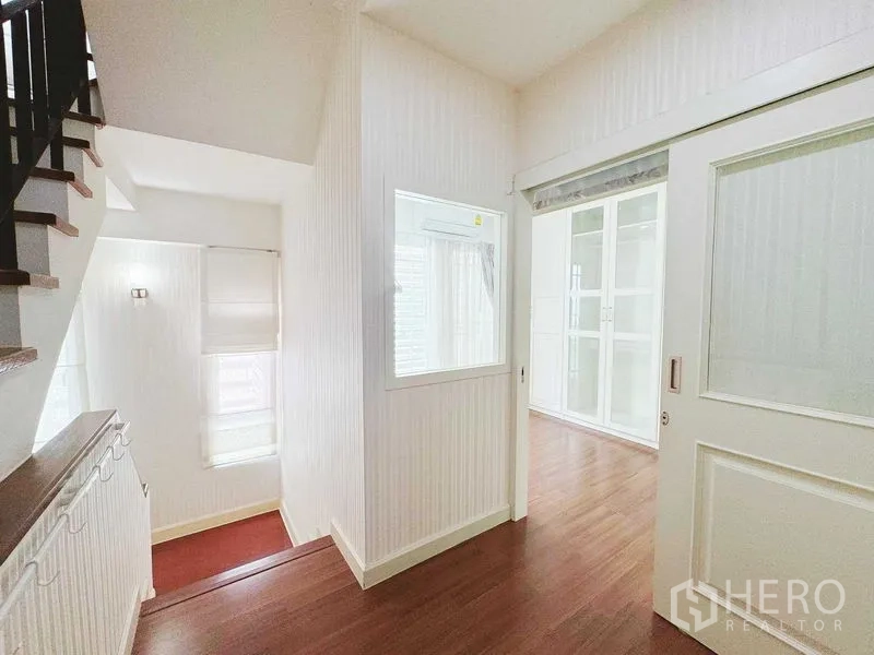 Townhouse for rent in Phra Khanong, Bangkok - Bright upper landing with sliding door and staircase.