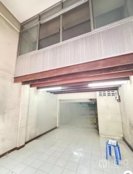 店屋 出租在Watthana, Bangkok - 一层店面大厅，白色地砖、外露木梁与上方玻璃窗。