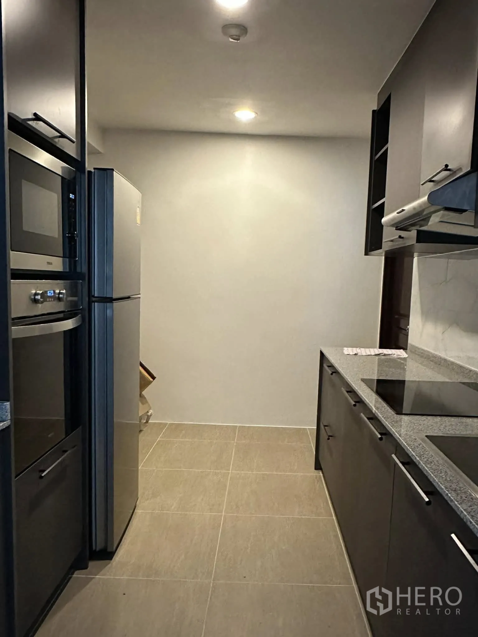 Condominium for rent in Pathum Wan, Bangkok - Kitchen featuring a refrigerator, built-in oven and microwave, and ample cabinets.