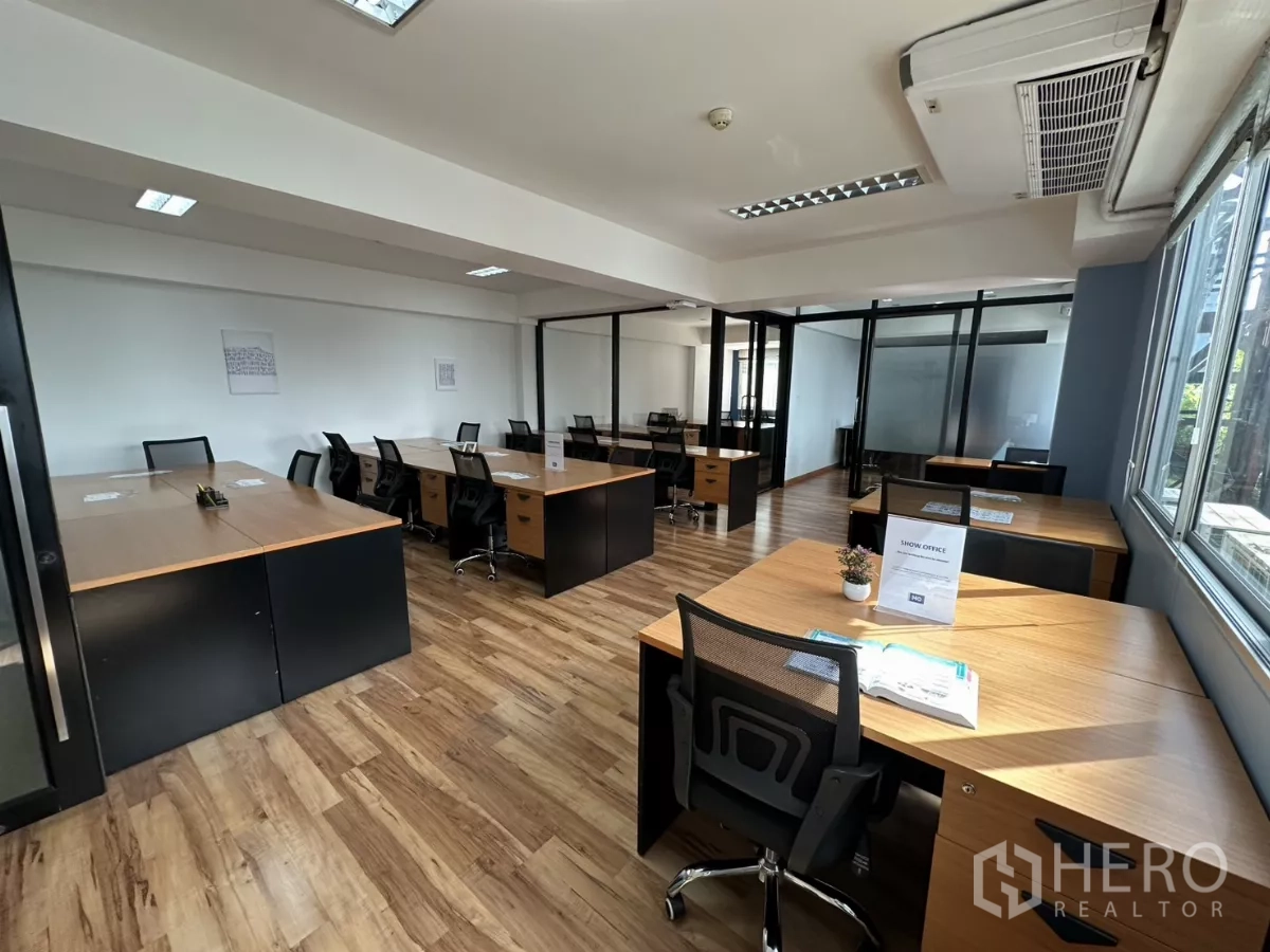 办公空间 出租在Watthana, Bangkok - 带家具的工作区，配备多张桌椅与空调，充满自然采光。
