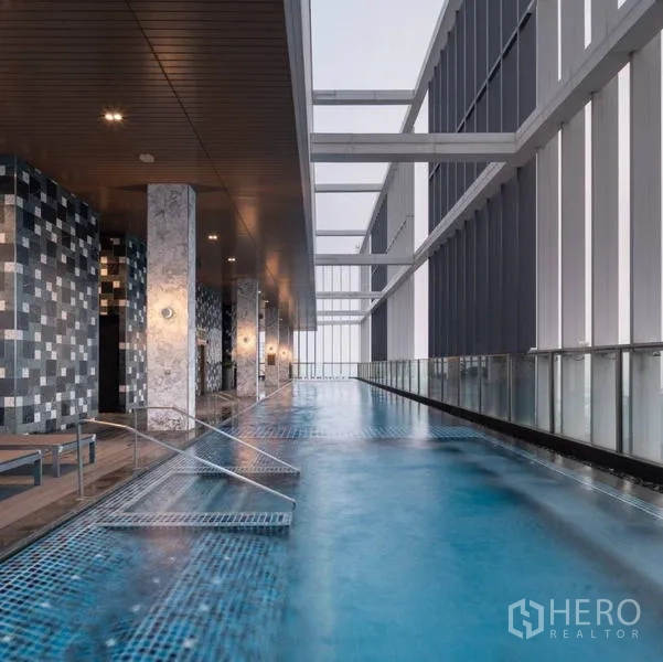 Condominium for rent - Covered sky lap pool with lounge chairs and glass balustrade overlooking the city skyline.