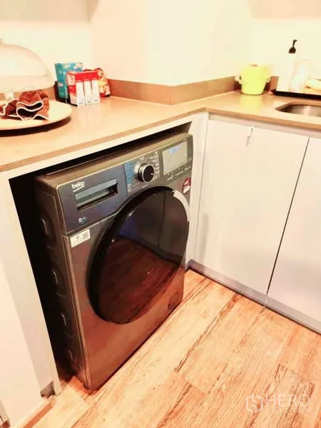 Condominium for sale in Bang Rak, Bangkok - Laundry corner with front-loading washer-dryer built under the countertop beside the sink.