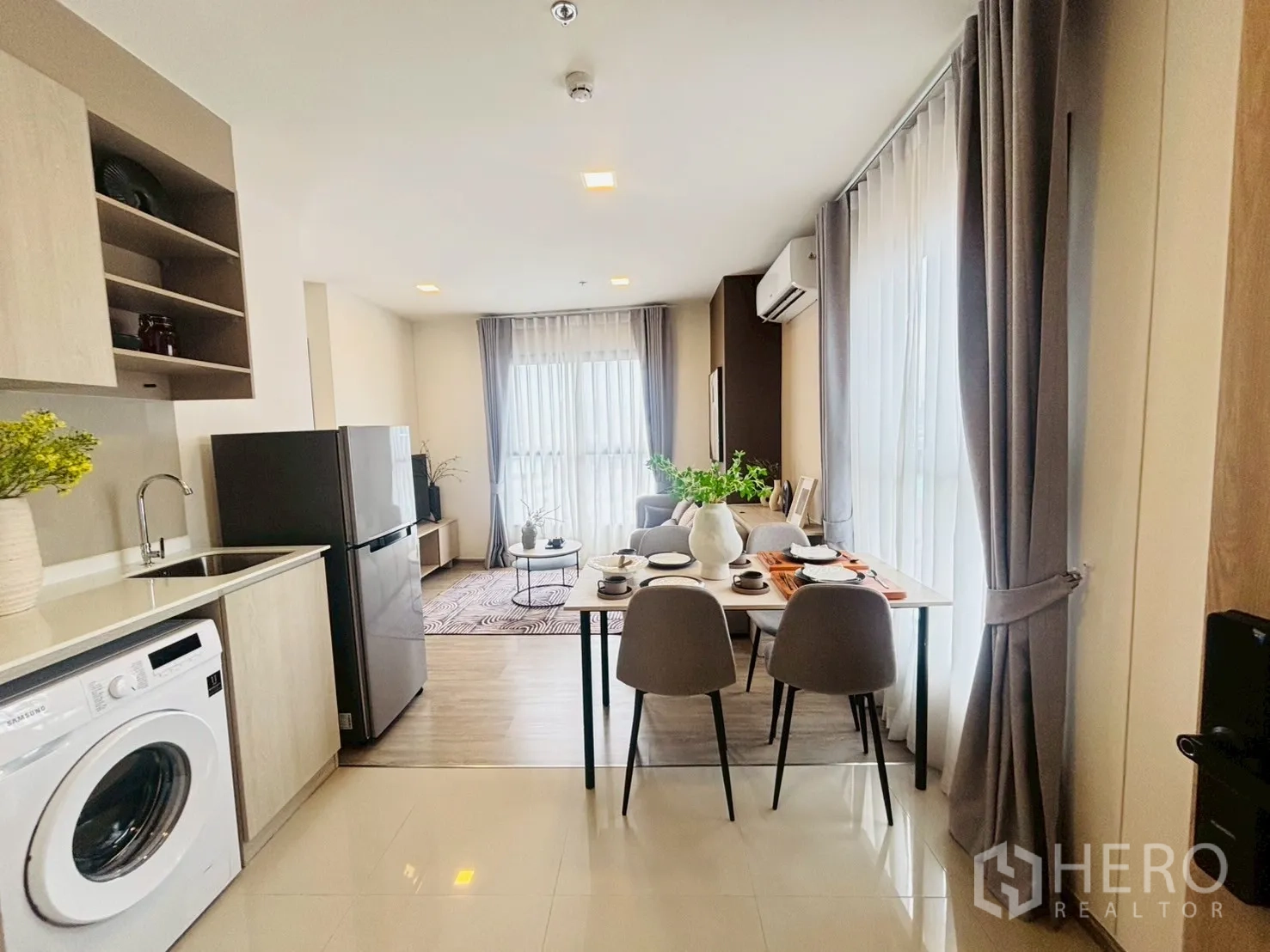 公寓 for rent in Watthana, Bangkok - 开放式厨房配洗衣机、冰箱和餐桌，旁边是落地窗与客厅。