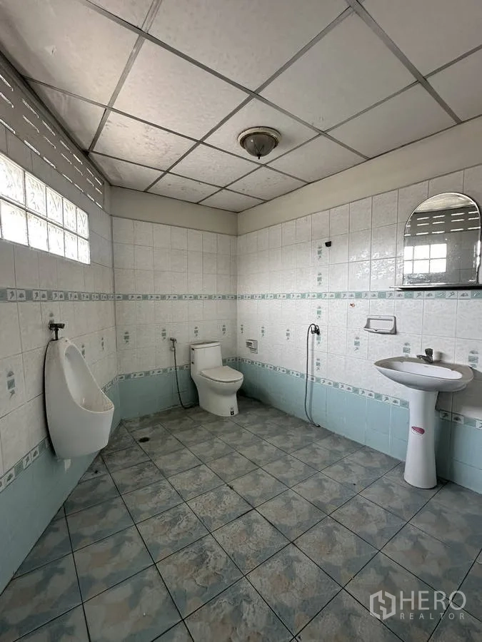 Home Office for rent in Taling Chan, Bangkok - Tiled restroom with toilet, urinal, pedestal sink and ventilation glass blocks.