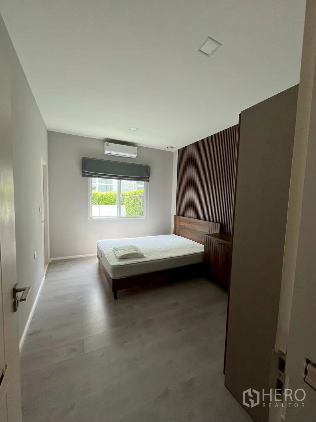 Detached House for rent in Prawet, Bangkok - Guest bedroom with wood slat headboard, wardrobe and window.