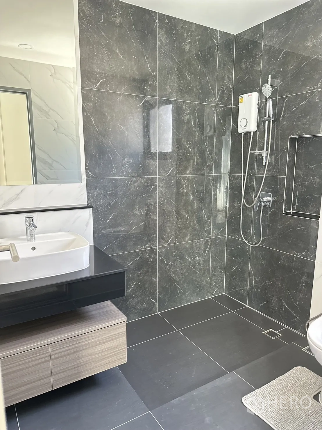 Detached House for rent or sale - Modern bathroom with dark stone tiles, open shower area, wall-mounted vanity and water heater.