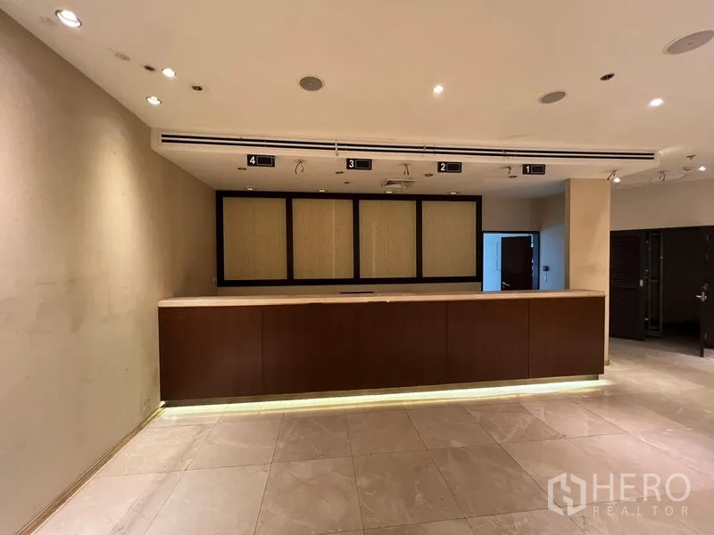 Retail Space for rent - Modern retail interior with a long wood reception counter, spotlights, and tiled floor.