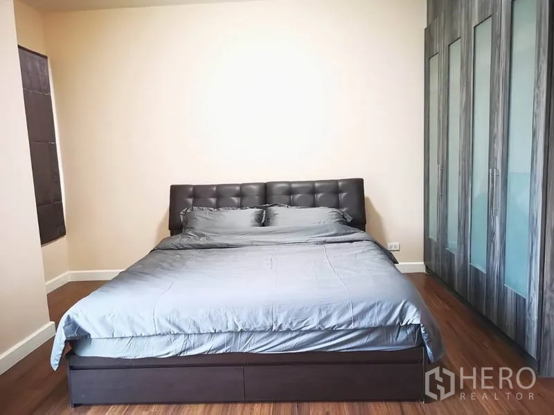 Townhouse for rent in Suan Luang, Bangkok - Bedroom with upholstered bed and full-height wardrobes on wood flooring.