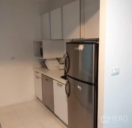 Condominium for rent in Pathum Wan, Bangkok - Separate kitchen with white cabinetry, countertop, and stainless-steel refrigerator.