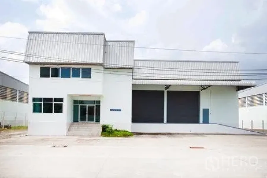 Warehouse for rent in Bang Phli, Samut Prakan - Facade showing two large roller shutters, a covered loading dock, and a parking apron.