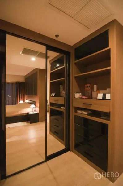 Condominium for rent in Khlong Toei, Bangkok - Walk-in closet with mirrored sliding doors and built-in cabinetry providing ample storage.