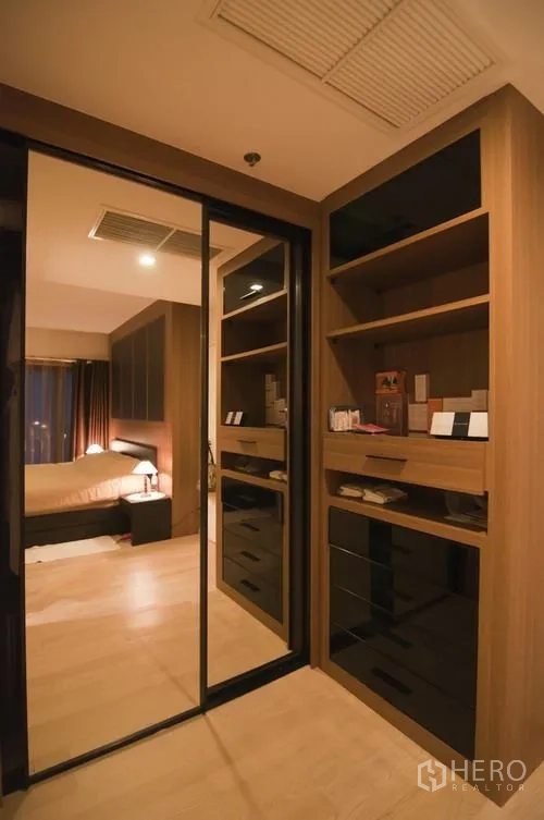 Condominium for rent in Khlong Toei, Bangkok - Walk-in closet with mirrored sliding doors and built-in cabinetry providing ample storage.