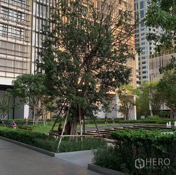 Condominium for rent in Khlong Toei, Bangkok - Landscaped condominium garden with mature trees and modern high-rise buildings.