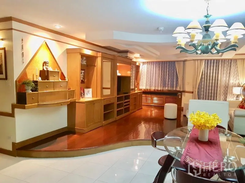 公寓 出租在Watthana, Bangkok - 温馨客厅，带木质一体化电视柜、玻璃餐桌与吊灯照明。