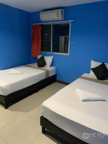 Retail Space for rent in Khlong Toei, Bangkok - Twin-bed room with blue walls, air conditioner and curtained window.