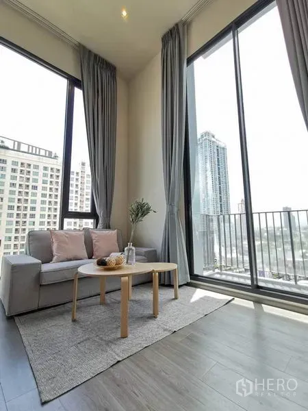 公寓 出租在Phaya Thai, Bangkok - 舒适沙发角落，落地窗与阳台，木地板采光好。