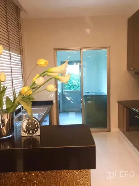 Detached House for sale in Lat Krabang, Bangkok - Kitchen view toward utility room through sliding glass door with counter and sink.