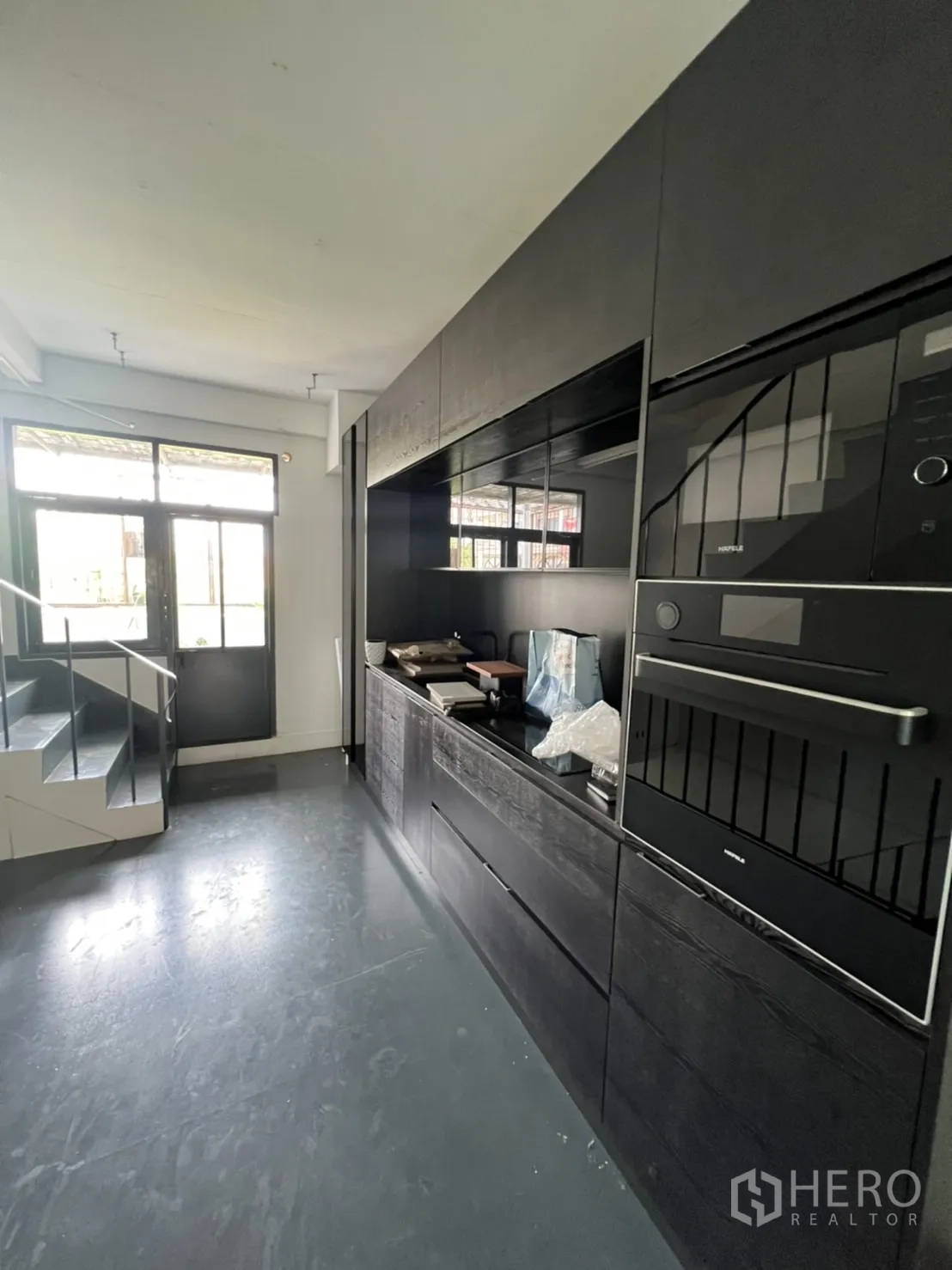 Shophouse for rent or sale in Watthana, Bangkok - Built-in black pantry with wall ovens beside the staircase at the shophouse entrance.